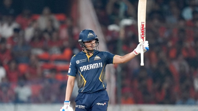Shubman Gill raises his bat to acknowledge the crowd after a milestone during an IPL 2025 match, wearing the Gujarat Titans jersey.