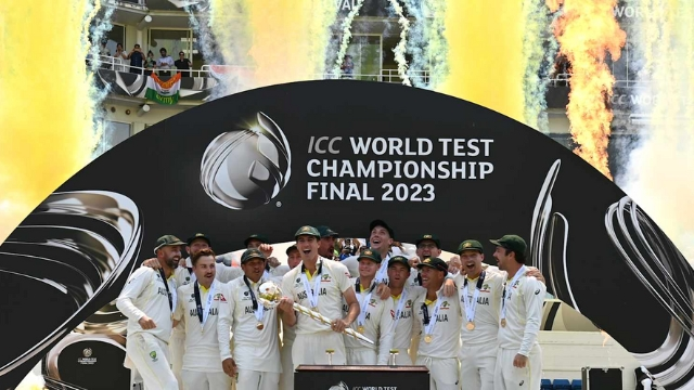 Australian men's cricket team celebrates winning the ICC World Test Championship Final 2023 with trophy and fireworks in the background.
