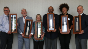 Group photo of ECB's inaugural Honorary Life Vice Presidents holding framed cricket bat awards.