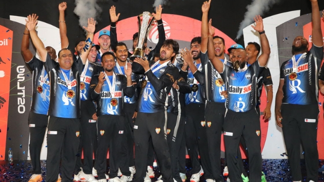 Players of the Global Super League 2025 champion team celebrating with trophy on stage, wearing matching jerseys and medals.