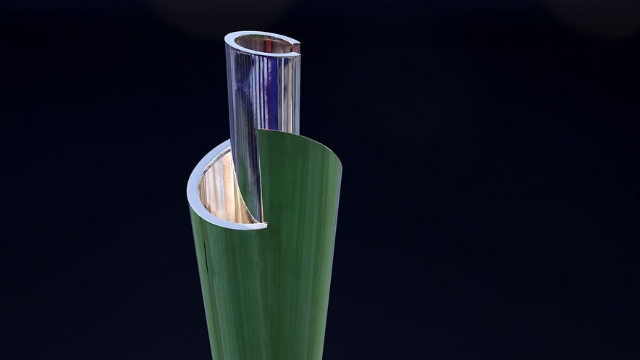 Close-up view of the ICC cricket trophy with a sleek green and silver spiral design against a dark background.
