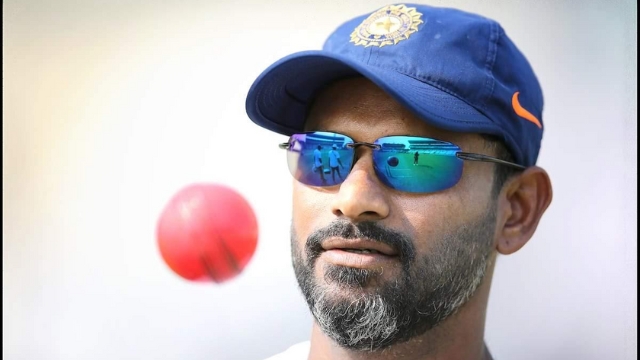 India fielding coach R. Sridhar wearing sunglasses and cap, focused on a red ball during training session.