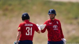 England cricketers Ronnie Jackson and Henry Wainman fist-bump during a T20I match in 2025, wearing red and blue team kits.
