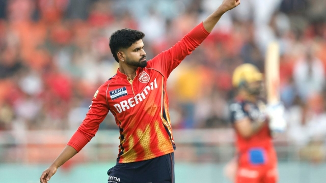 Shreyas Iyer, captain of Punjab Kings, gestures on the field during an IPL match with a blurred batter in the background.