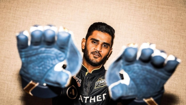 Cricketer Urvil Patel posing with gloves in Gujarat Titans jersey, showing a confident look ahead of the 2025 season.