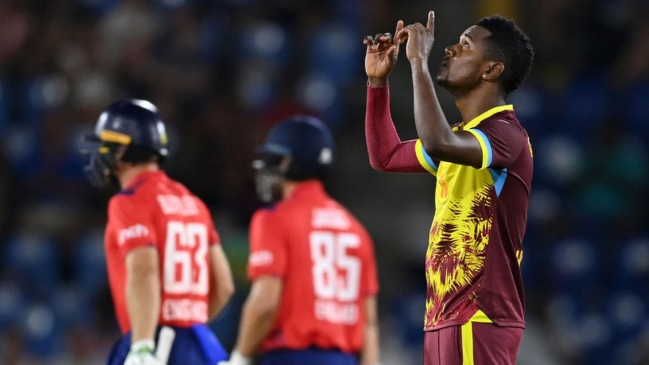 West Indies cricketer Akeal Hosein celebrates during an ODI match against England, with opposing players in the background.