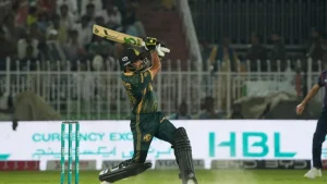 Babar Azam plays an aggressive shot during a Pakistan Super League (PSL) match, wearing his team's kit under stadium floodlights.