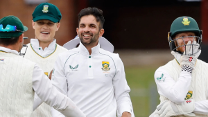 Keshav Maharaj smiling and celebrating with South African teammates in test cricket jerseys during a match.