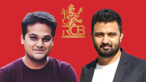 Praanesh Bhuvaneswar and Aditya Gurwara posing in front of the Royal Challengers Bengaluru (RCB) logo on a red background.
