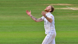 England's Ben Stokes celebrates on the field during a Test match, looking upward with arms raised in an emotional moment.