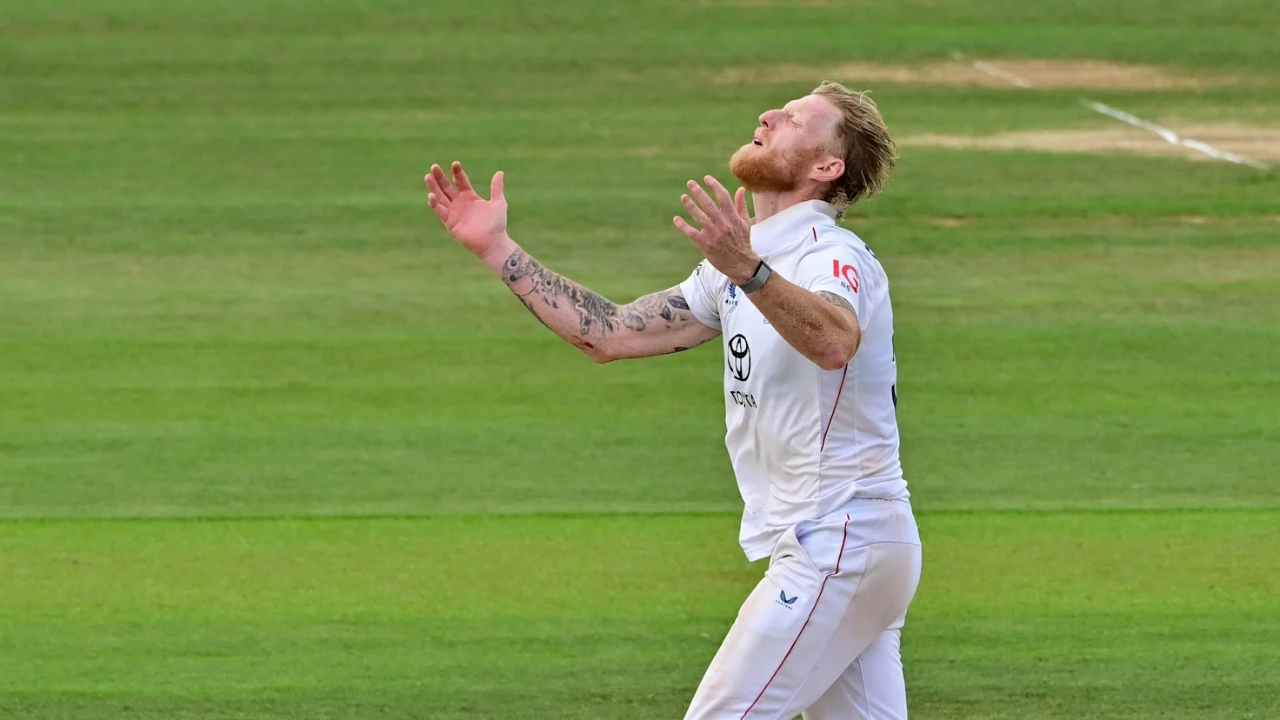 England's Ben Stokes celebrates on the field during a Test match, looking upward with arms raised in an emotional moment.