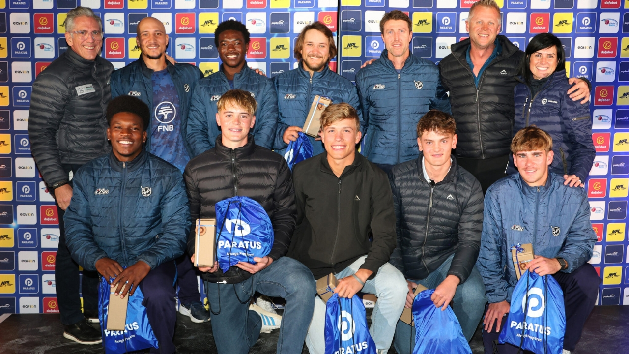 Group photo of players and officials at the Cricket Namibia event launching the 2025 T20 Franchise Competition, with team members holding branded Paratus gift bags and awards in front of a sponsor backdrop.