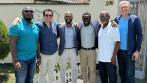 Dr. Kishore Shallow, President of Cricket West Indies, standing with cricket officials and colleagues outside a building, all smiling and posing for the camera.