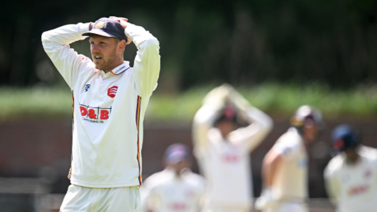 England cricketer in a white jersey showing a disappointed reaction during a County Championship match.