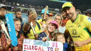 Faf du Plessis wearing a Joburg Super Kings jersey posing with enthusiastic fans holding bats and signs at a cricket stadium.
