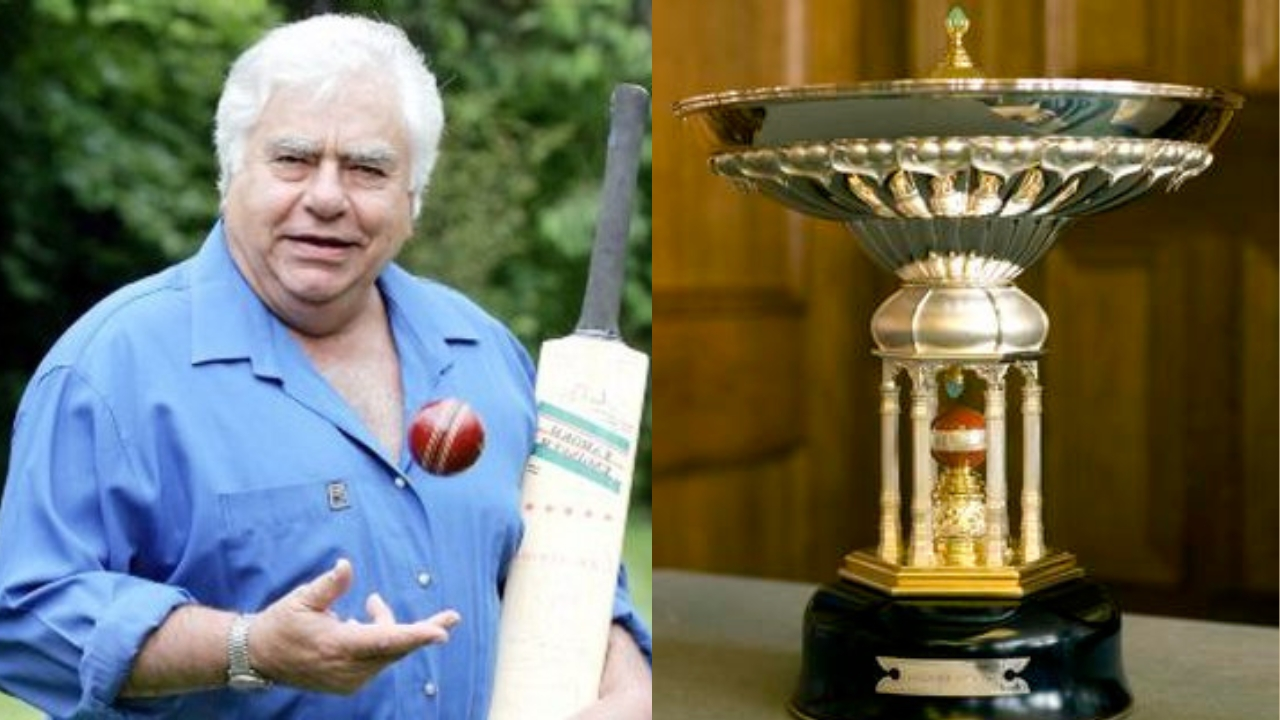 Former Indian cricketer Farokh Engineer holding a cricket bat, with the Pataudi Trophy displayed beside him.