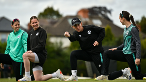 Ireland women's cricket team players warming up during a practice session on the field.