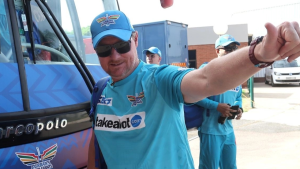 Lance Klusener, head coach of Durban’s Super Giants, gives a thumbs up while wearing team gear and standing beside the team bus.