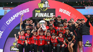 Melbourne Renegades women's cricket team celebrating their WBBL10 championship win, holding the trophy and posing under the finals arch with medals and "Champions" caps.