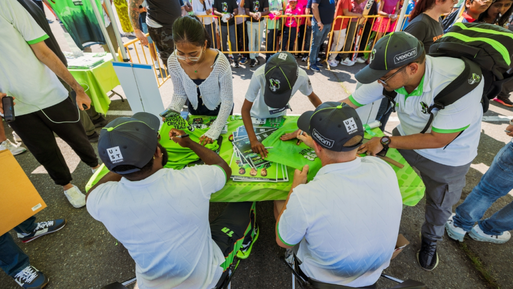 Seattle Orcas players signing autographs for young fans at an outdoor fan meet-and-greet event.