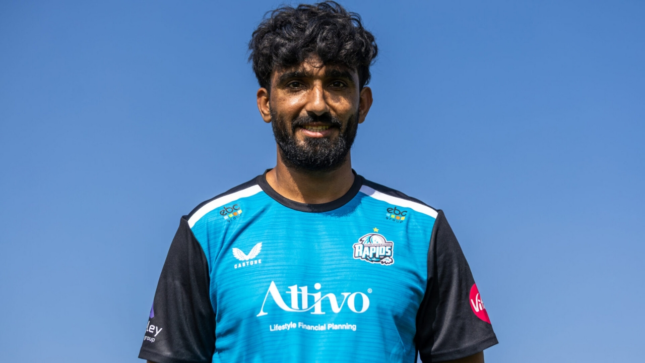 Usama Mir posing in Worcestershire Rapids cricket jersey against a clear blue sky.