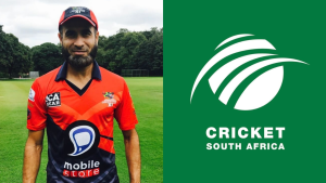 Imran Tahir in red cricket jersey standing on field next to Cricket South Africa logo