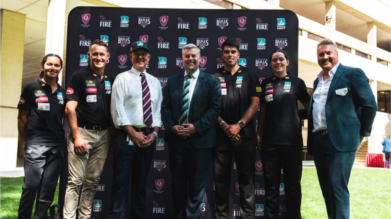 Queensland Cricket officials and players from Bulls and Fire teams posing at a launch event with branding backdrop