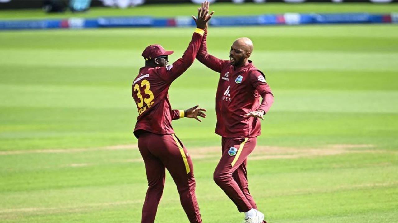 West Indies cricketer Roston Chase celebrating with a teammate in maroon ODI kit during an international cricket match.