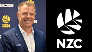 Scott Weenink standing in front of the New Zealand Cricket (NZC) logo backdrop, smiling in a formal suit.