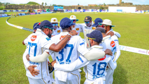 Sri Lanka national cricket team players in white Test kits forming a huddle on the field before a match.