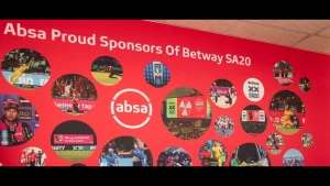 Absa branding on red wall showcasing sponsorship of Betway SA20 cricket league with action images and promotional visuals