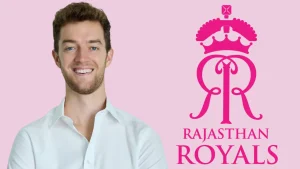 Jake Lush McCrum, CEO of Rajasthan Royals, smiling in a white shirt beside the team’s pink logo on a light background.