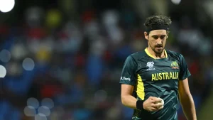 Mitchell Starc holds the ball while preparing to bowl during a T20I World Cup match for Australia, wearing the national team's dark green jersey.