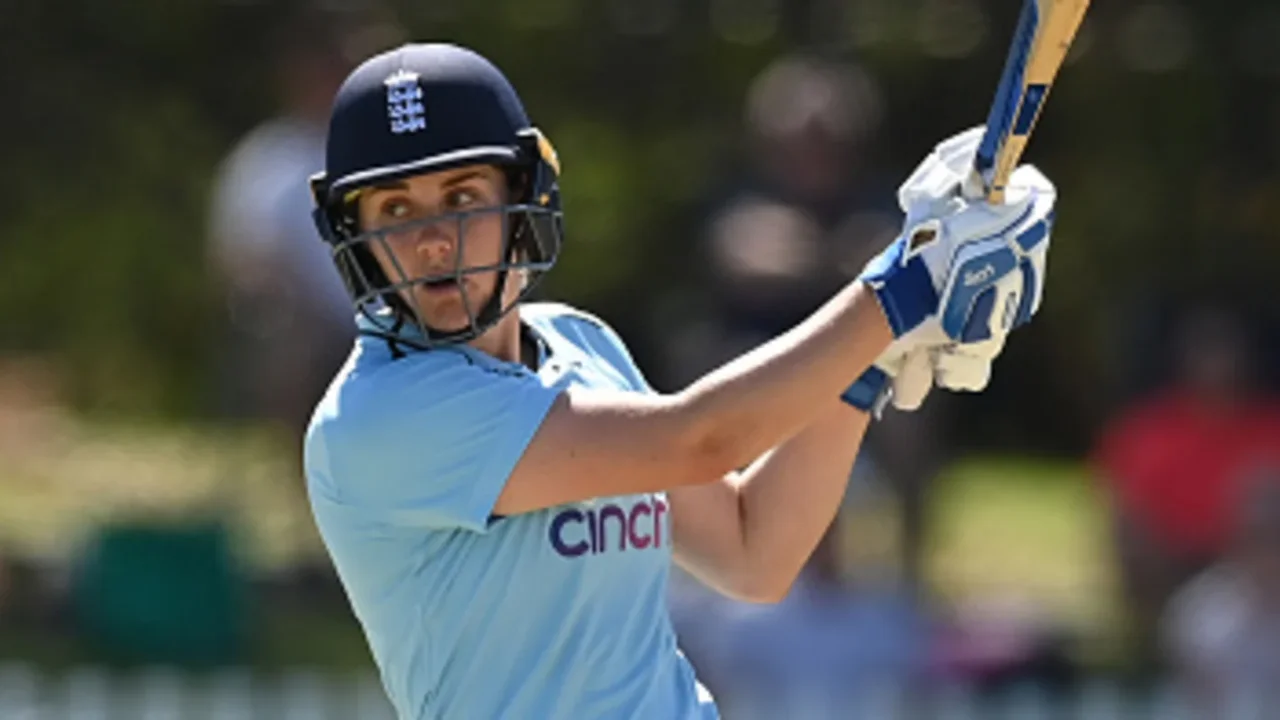 England cricketer Nat Sciver-Brunt plays a shot during a match, wearing batting gear and light blue jersey with helmet