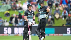 Two New Zealand cricketers in ANZ-branded black and teal uniforms standing at the crease during a T20I match