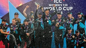 New Zealand women’s cricket team celebrating with champagne after winning the ICC Women’s T20 World Cup 2024, holding the trophy and wearing gold medals on stage.