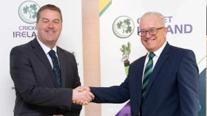 Cricket Ireland officials Ross McCollum and Brian MacNeice shaking hands and smiling at a leadership event.