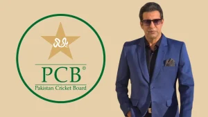 Wasim Akram in a blue suit posing next to the PCB (Pakistan Cricket Board) logo