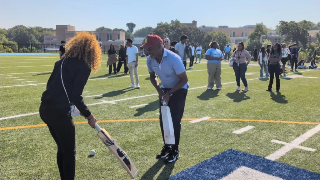Brian Lara teaching cricket to a student on a school field during an outreach and engagement session