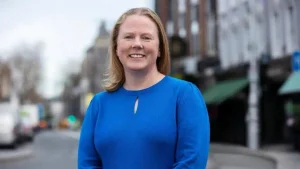 Ciara O’Brien smiling in a blue dress with a city street background