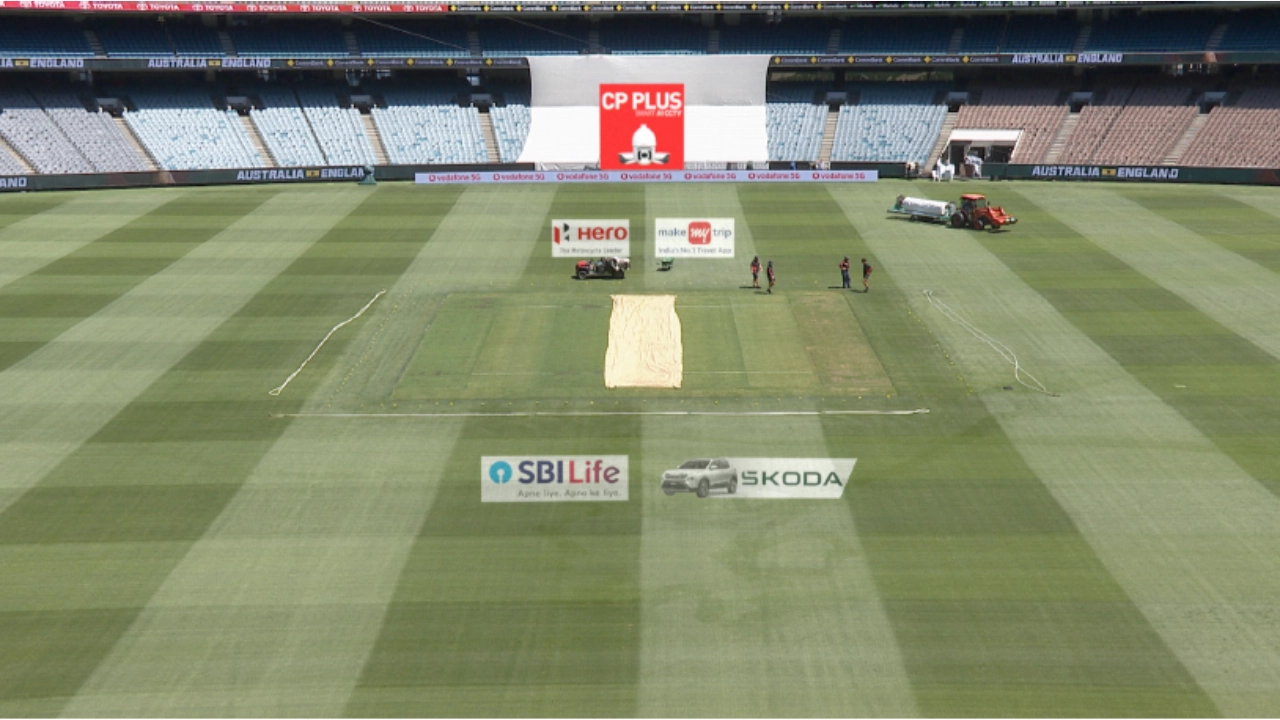Groundsmen preparing the cricket pitch in an empty stadium with Australia vs England banners and visible field advertisements