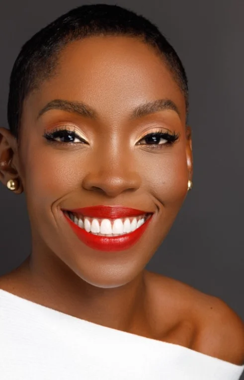 Dr. Tara Wilkinson smiling confidently in a professional portrait, wearing a white outfit with bright red lipstick and gold earrings.
