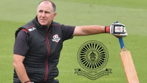 Gary Stead in Canterbury cricket gear resting with a bat on a field, with the Andhra Cricket Association logo beside him