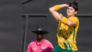 Gerald Coetzee bowling in a match wearing South Africa cricket jersey with ICC umpire in the background