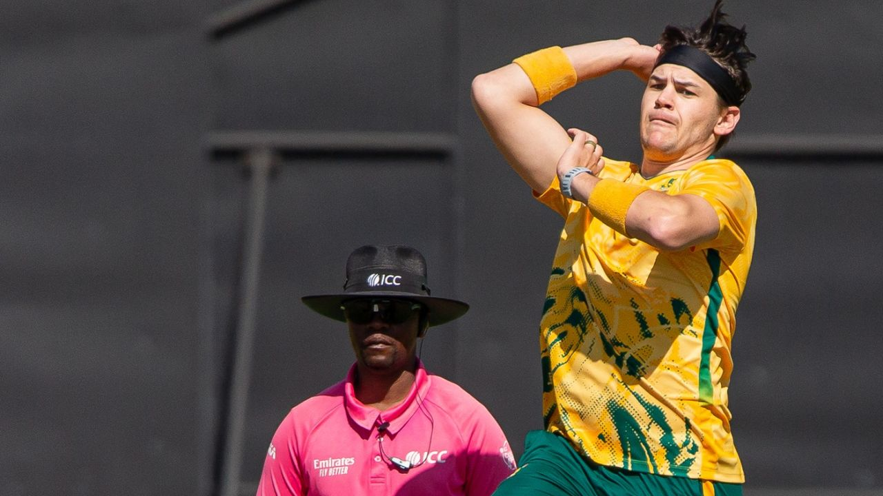 Gerald Coetzee bowling in a match wearing South Africa cricket jersey with ICC umpire in the background