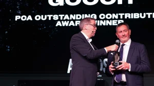 Graham Gooch receiving the PCA Outstanding Contribution Award on stage, holding the trophy during the ceremony.