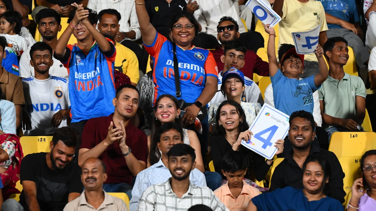 Indian cricket fans cheering and holding scorecards during a live match at the stadium