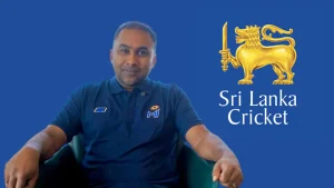 Mahela Jayawardene seated in front of the Sri Lanka Cricket logo on a blue background.