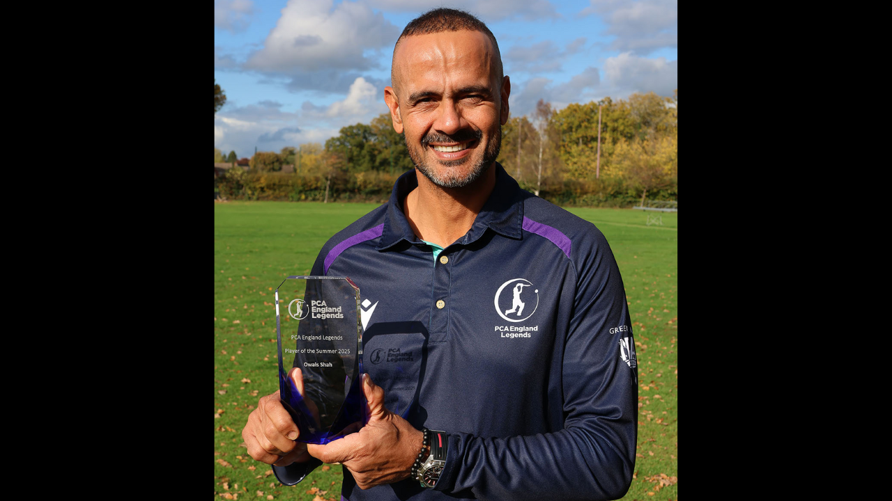 Owais Shah holding the PCA England Legends Player of the Summer 2025 award while smiling on a cricket field.
