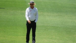 Cricket umpire Rodney Tucker walking on the field in ICC and Emirates Elite Panel uniform during a match.